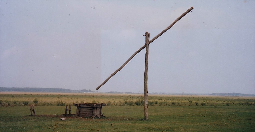 Paysage typique de la Puszta hongroise, avec un puits traditionnel et une vaste plaine à l’horizon.